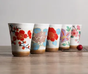 Set of five Japanese-style ceramic tea cups with colorful floral patterns and rustic clay base