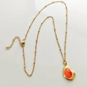 Detail of vintage 18K gold-plated stainless steel necklace with orange cabochon pendant