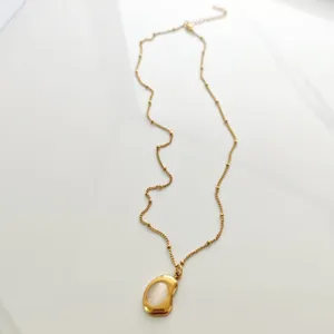 Close-up of retro 18K gold plated stainless steel necklace with organic pendant inlay.