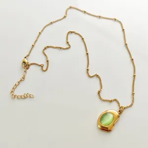 Detail view of 18K gold plated necklace featuring an organic green stone pendant