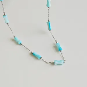 Close-up of stainless steel necklace featuring light blue bamboo-shaped beads with texture