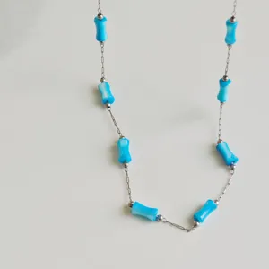 Close-up detail of stainless steel necklace featuring light blue bamboo joint beads.