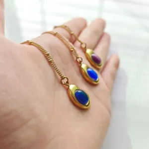 Macro detail of retro 18K gold-plated stainless steel necklaces with blue oval stone pendants