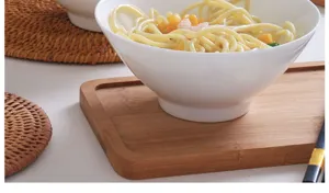 Dettaglio ravvicinato di una ciotola di ceramica bianca su un vassoio di legno con pasta