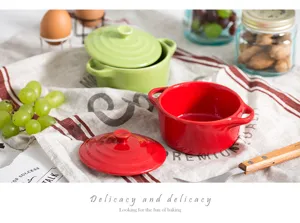 Detail of red and green double-handle ceramic baking dishes with lids on a rustic tea towel.