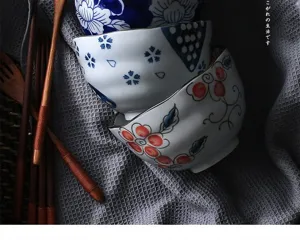 Stack of Japanese style ceramic bowls with intricate floral patterns on textured grey cloth