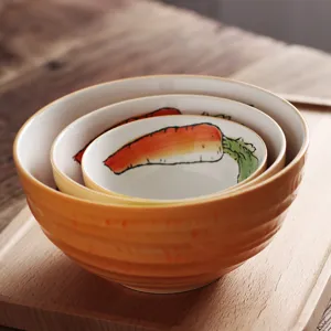 Gros plan sur le motif carotte peint à la main des bols japonais emboîtables en céramique.