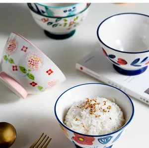 Detail of hand-painted ceramic Japanese rice bowls with floral patterns on a table.