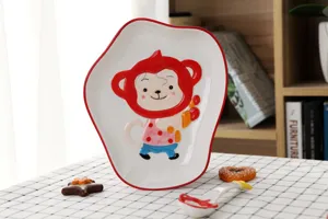Gros plan d'une assiette irrégulière en céramique avec un mignon singe peint à la main