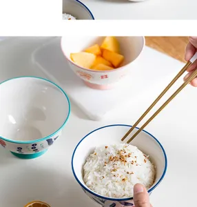 Detailed macro view of a hand-painted Japanese ceramic rice bowl with golden chopsticks.