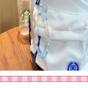 Detailopname van een blauwe en transparante sterren kralen hanger aan een witte rugzak