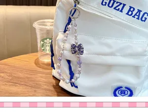 Detailed view of a sparkling rhinestone blue bow beaded strap with white pearls on a bag