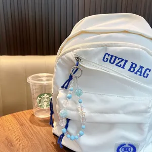 Handgemaakte sleutelhanger met blauwe sterrenkralen aan een witte rugzak hangend