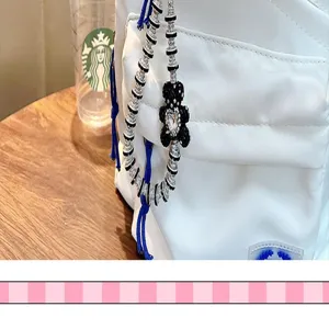 Macro view of a black rhinestone bear keychain hanging on a stylish white backpack