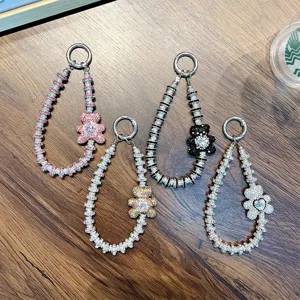 Luxury rhinestone bear lanyard and keychain charms displayed on a wooden table.