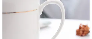 Detalle del elegante borde dorado y el asa curva en una taza de cerámica blanca