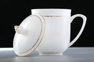Vista detallada de una elegante taza de té de porcelana blanca con borde dorado y tapa
