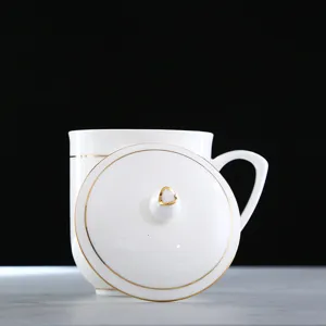 Detalle de una elegante taza de porcelana blanca con borde dorado y tapa a juego.