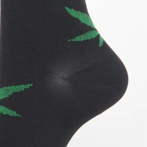 Macro detail view of a black sport compression sock heel with green leaf knit pattern