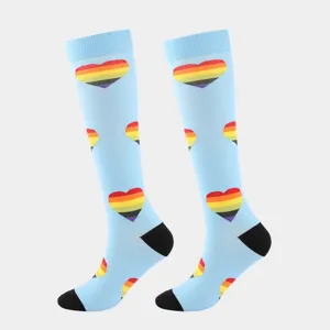 Detailansicht hellblauer Kompressionsstrümpfe mit lebendigen Regenbogen-Herzmustern am Bein
