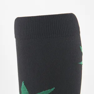 Detailed macro shot of black athletic compression sock cuff with green leaf pattern