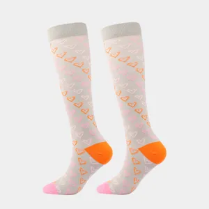Detailansicht von kniehohen Kompressionsstrümpfen mit rosa und orangefarbenen Herzen.