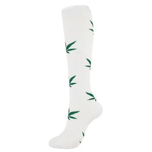 Close-up view of white sports compression calf socks featuring a green leaf pattern design