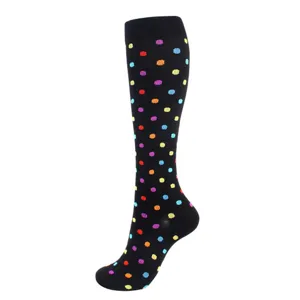 Gros plan d'une chaussette de compression noire ornée d'un motif à pois colorés éclatants.