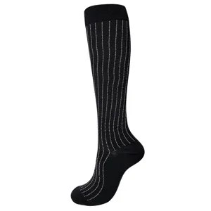 Gros plan d'une chaussette de compression noire avec un motif de rayures à pois blancs verticaux