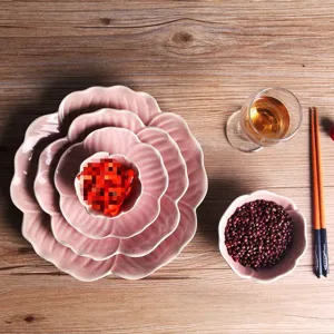 Japanese style pink flower petal ceramic tableware set featuring nested plates on wooden table