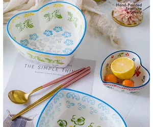 Macro detail of hand-painted heart-shaped ceramic bowl set with colorful floral patterns