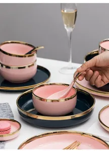 Luxuriöses rosa und dunkelblaues Keramik-Geschirrset mit Goldrand auf einem Tisch
