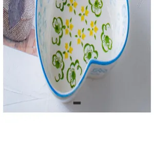 Macro detail of a heart-shaped ceramic bowl with green floral patterns and blue rim
