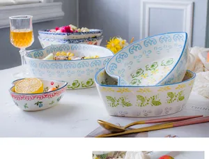 Hand-painted heart-shaped ceramic bowls with colorful floral patterns in lifestyle setting.