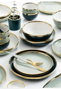 Nahaufnahme eines luxuriösen Keramikgeschirrs mit elegantem Goldrand in Grüntönen