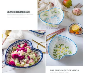 Detail view of heart-shaped ceramic bowls with hand-painted floral patterns and fruit