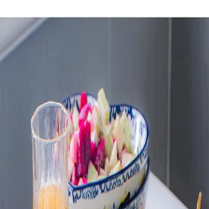 Detail view of a heart-shaped ceramic dessert bowl filled with fresh fruit salad on a table