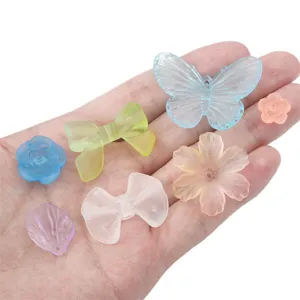 Vista detallada de dijes de acrílico esmerilato con formas de flores y mariposas para DIY