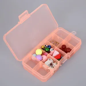 Macro view of 10-compartment orange plastic organizer box with beads and tassels inside.