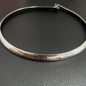 Gros plan d'un collier ras de cou omega en acier inoxydable argenté pour femmes