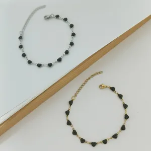 Detailed view of gold and silver stainless steel bracelets with black heart charms