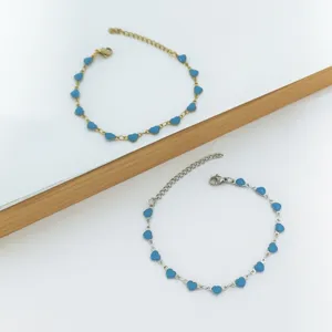 Close-up of gold and silver stainless steel bracelets with blue enamel heart charms.