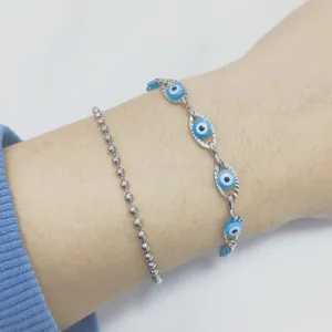 Primo piano di un set di braccialetti in acciaio inossidabile con l'occhio del male al polso