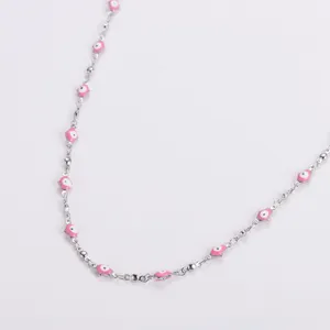 Close-up detail of a silver stainless steel necklace with pink Hamsa hand charms.