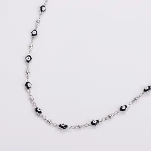 Close-up of stainless steel necklace featuring black and white Hamsa hand charms.