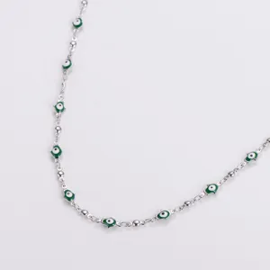 Close-up detail of silver stainless steel necklace with green evil eye Hamsa charms.