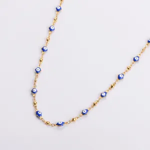Close-up detail of a gold stainless steel necklace with blue evil eye hamsa charms