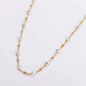 Detailed macro shot of a gold stainless steel Hamsa hand necklace with blue evil eye charms