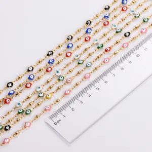 Close-up detail of stainless steel gold chain with colorful Hamsa evil eye palm charms