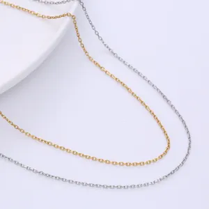 Macro detail showing gold and silver minimalist faceted cable chains on a white surface.